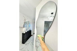 Reflection of woman spraying cleaning product on a mirror.